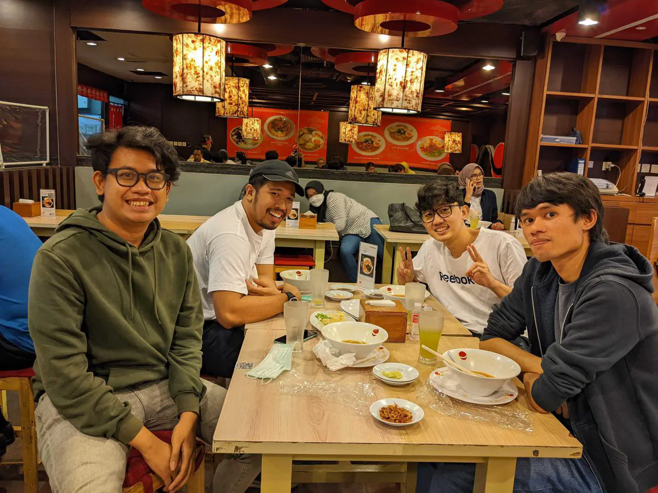 Four people smiling at a restaurant table with empty ramen bowls.