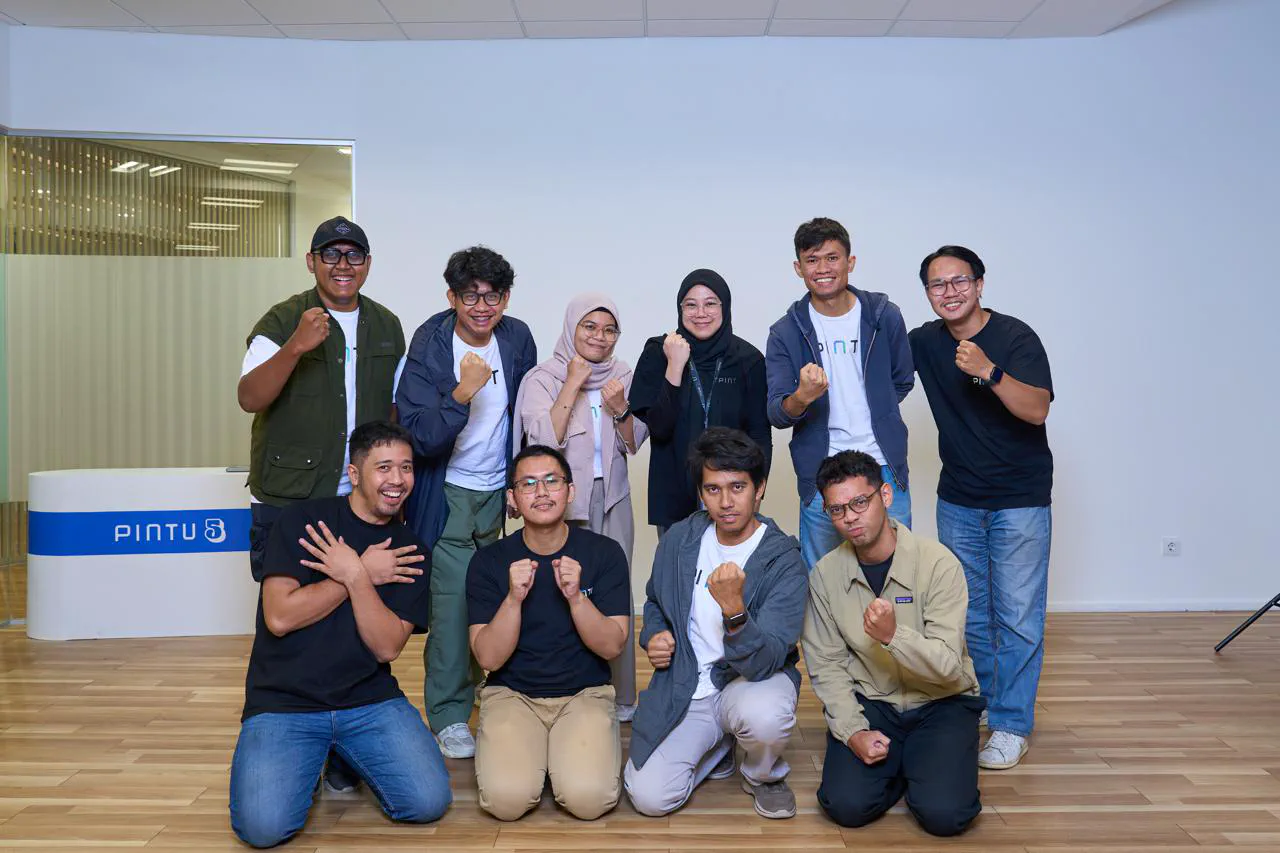 Ten members of the SRE team posing with raised fists in a white room, next to a PINTU 5 sign.